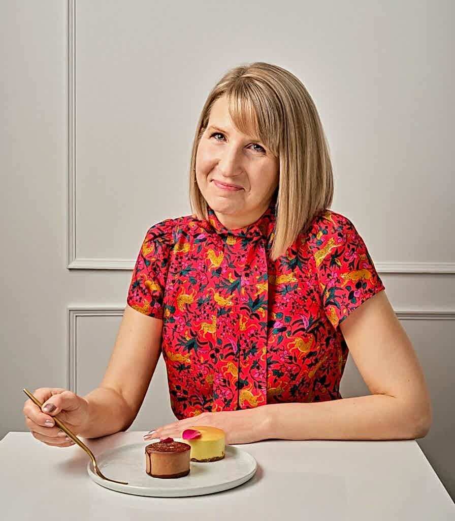 rebecca gade sawicki sitting at a small table with two round mini cakes in front of here in birmingham michigan