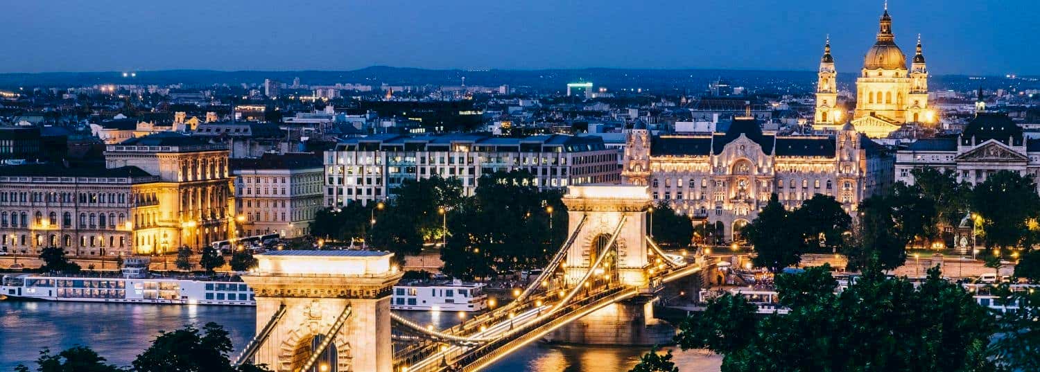 budapest chain bridge and city dimly lit at nighttime
