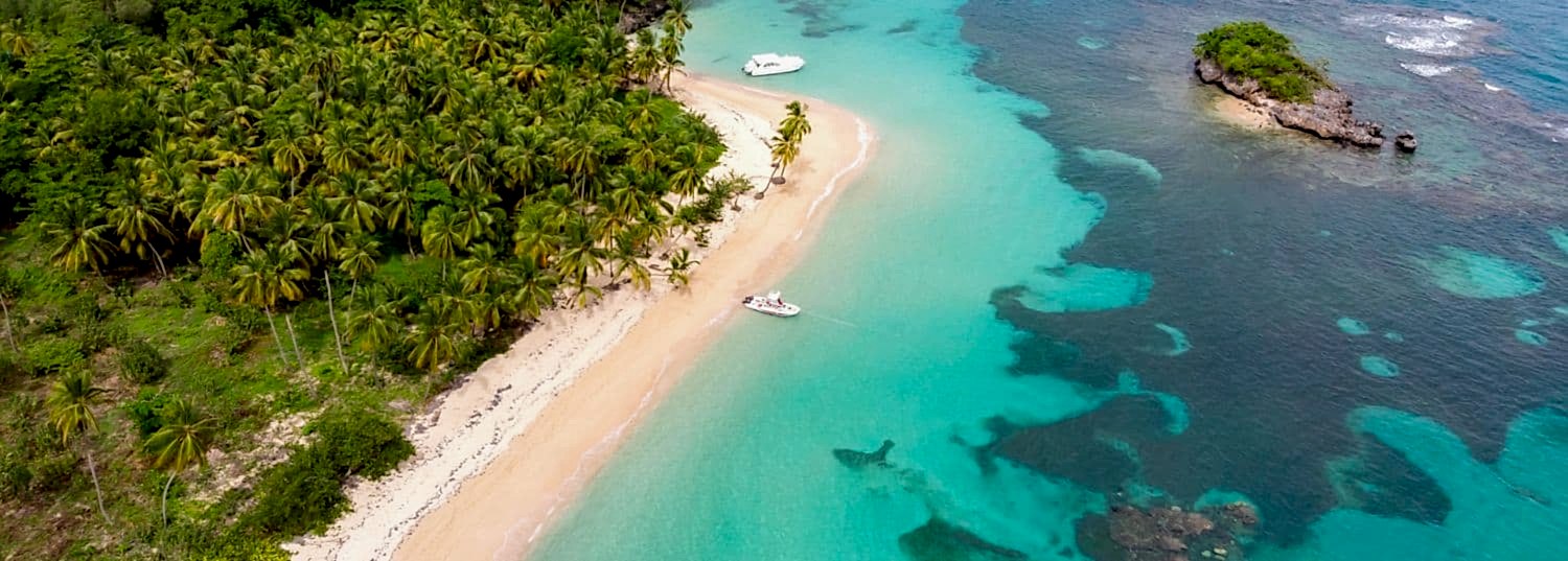overhead shot of a secluded white sand beach surrounded by turquoise waters in the caribbean