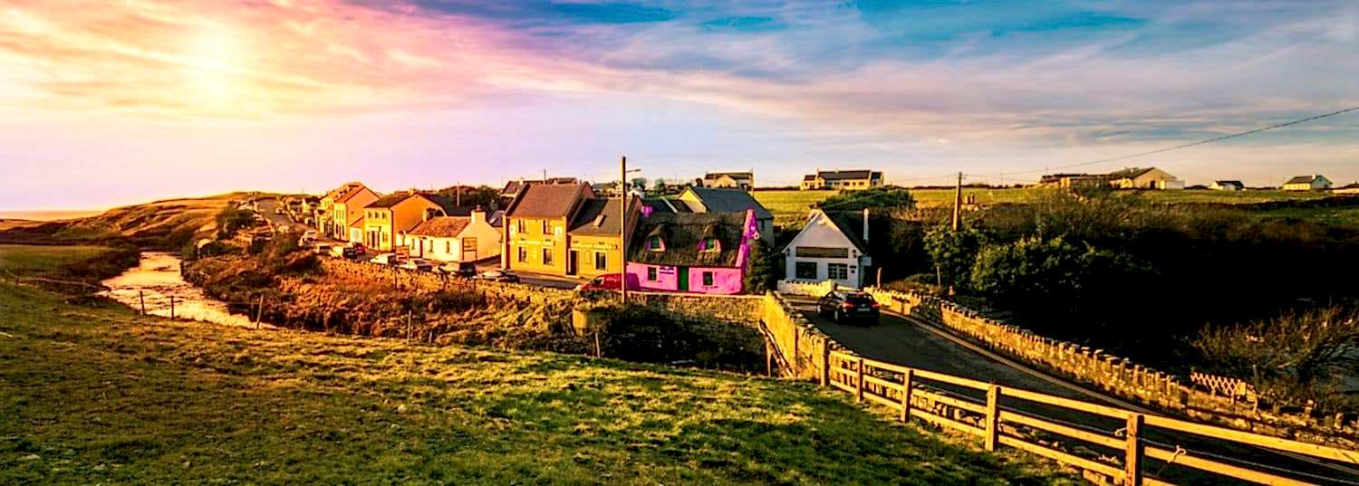 a quaint little village with colorful homes in the middle of the green countryside of ireland