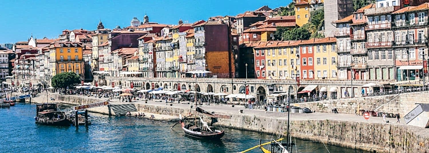 small boats in the river along a row of colorful buildings in porto, portugal
