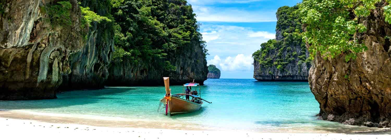 a secluded white sand beach in thailand with a single wooden boat sitting on the shore.