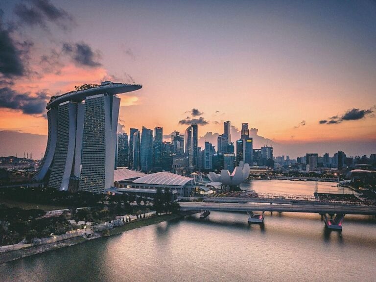 famous marina in singapore as the sun is setting with a pink and orange sky
