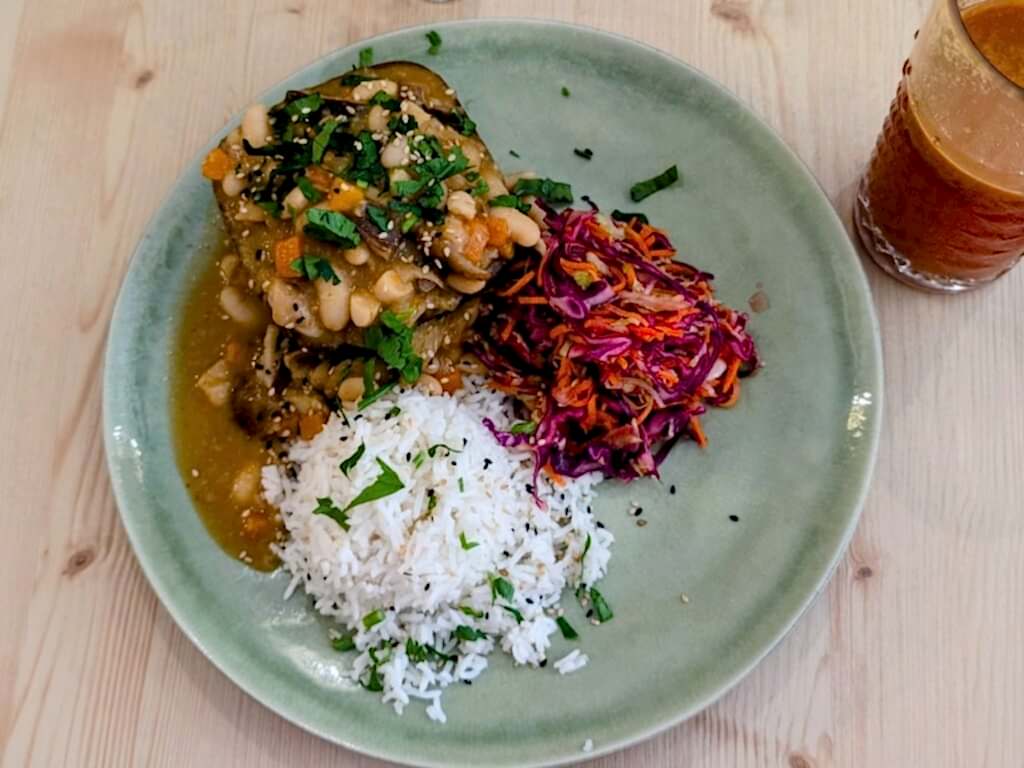 overhead view of a vegan portugese rice and bean stew with a mound of rice and red cabbage salad on a blue plate from the vegan restaurant o macrobiotico in porto